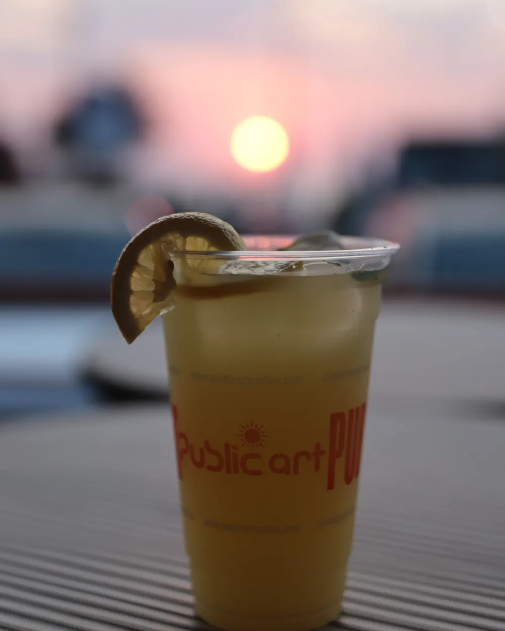A drink in a Public Art cup at sunset